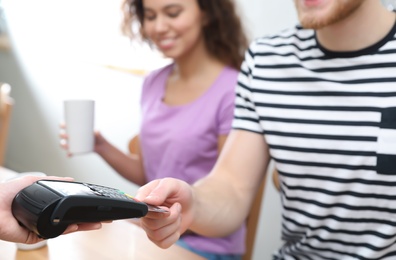 Photo of Clients using credit card machine for non cash payment in cafe, closeup