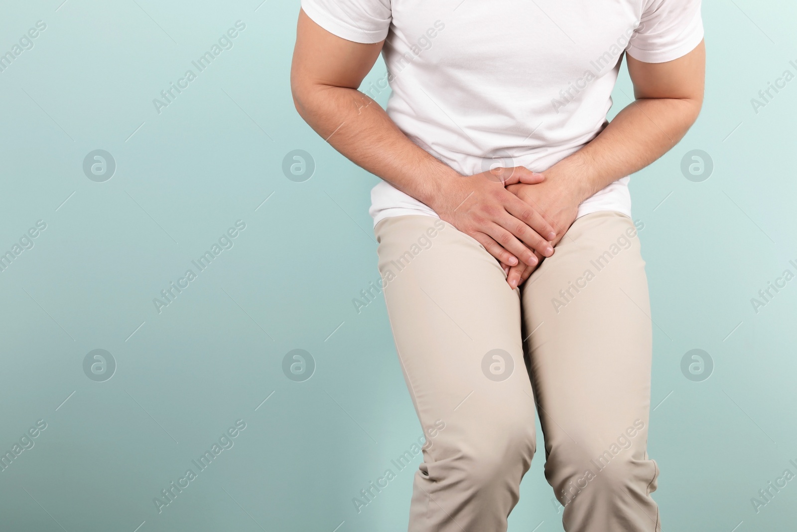 Photo of Young man with urological problems suffering from pain on color background