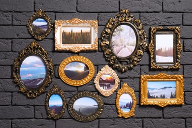Photo of Vintage frames with photos of beautiful landscapes hanging on dark brick wall