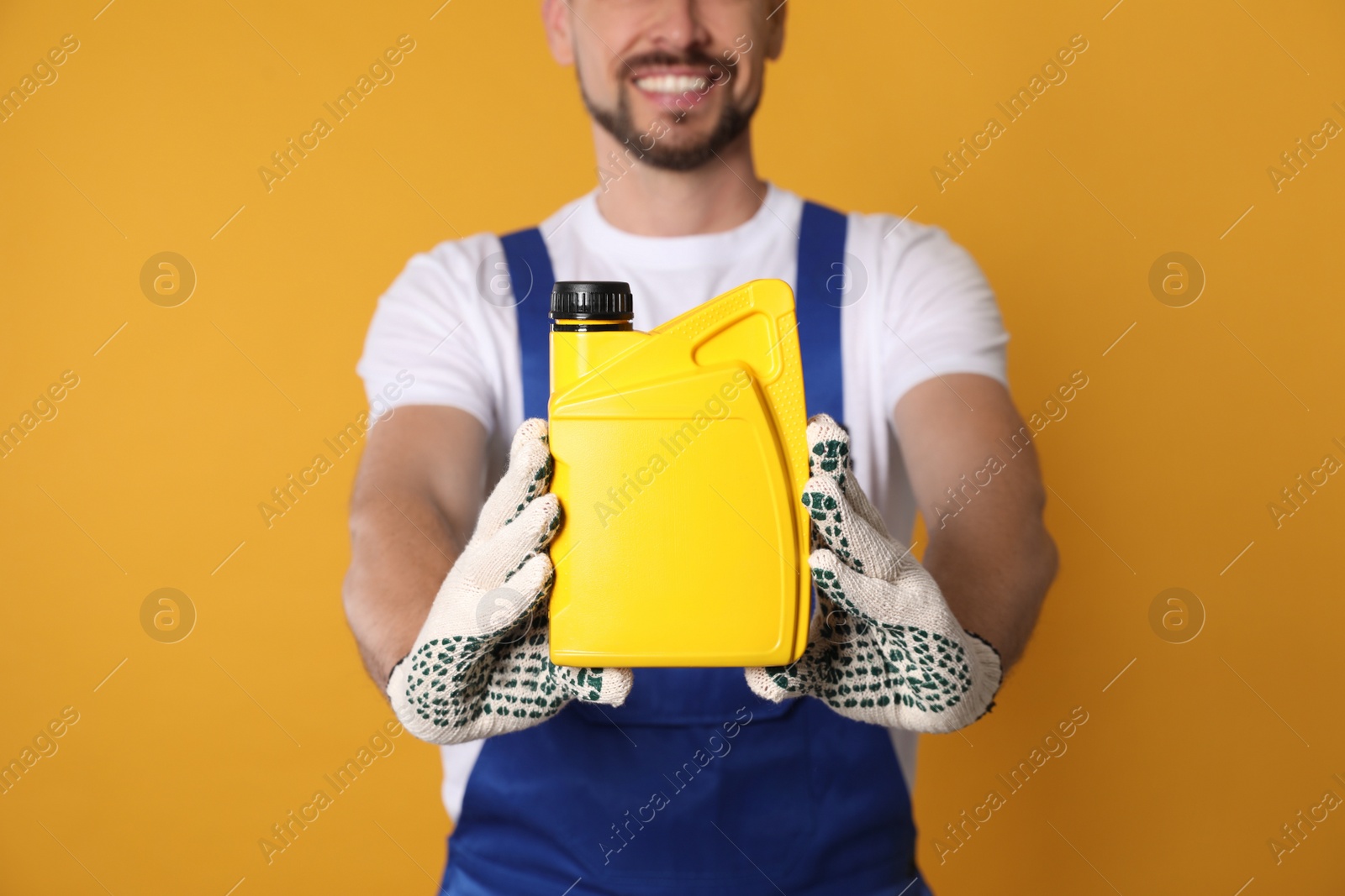 Photo of Man showing yellow container of motor oil on orange background, closeup