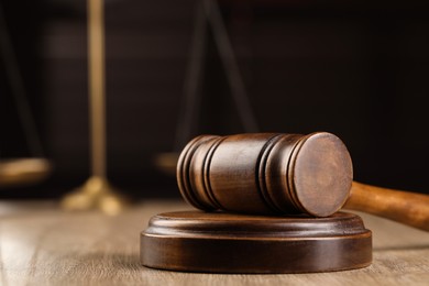 Photo of Wooden gavel on table against blurred background, closeup