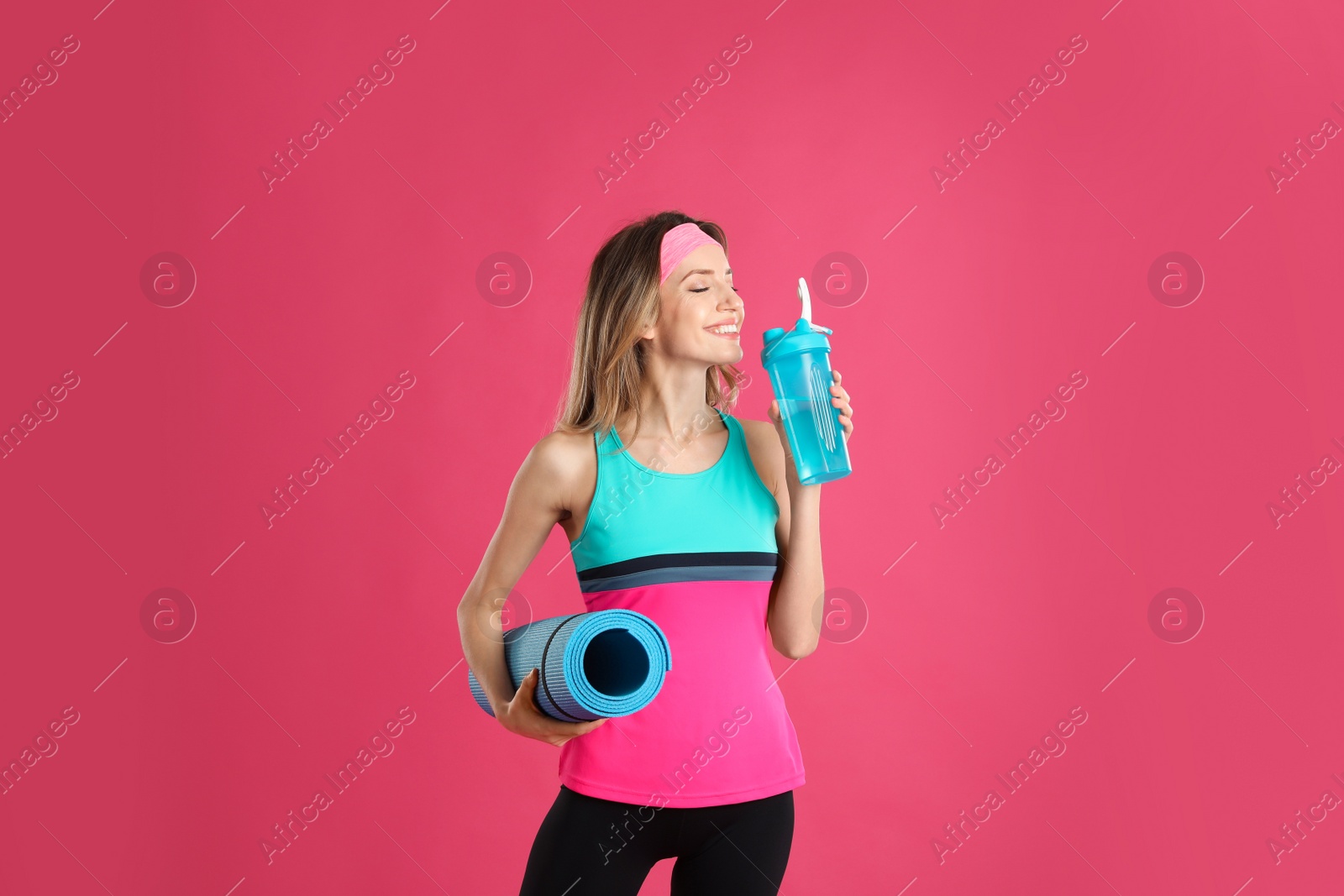 Photo of Beautiful woman with yoga mat and shaker on pink background