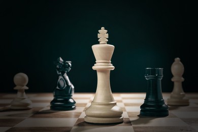 Image of Different game pieces on chessboard against dark background