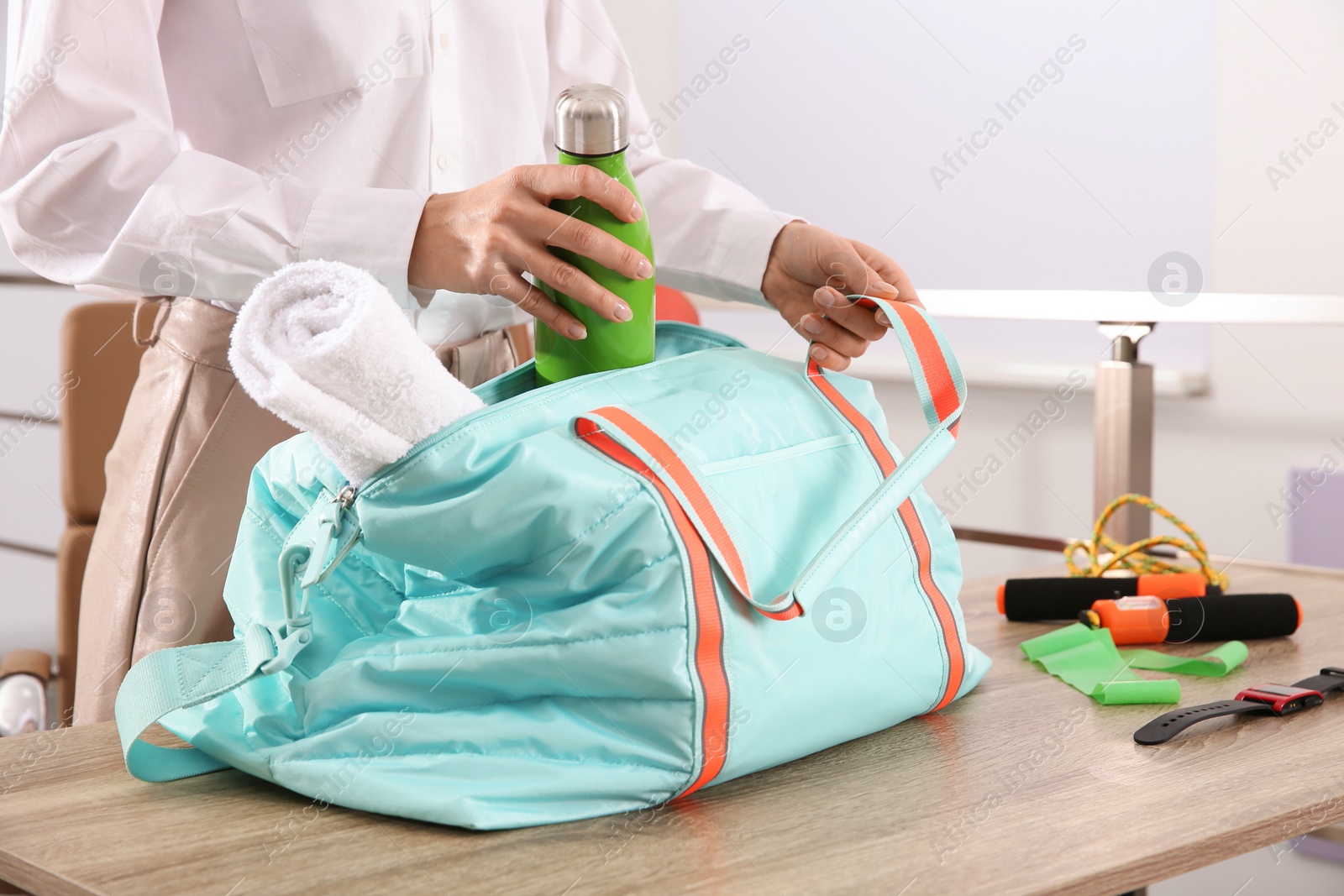 Photo of Businesswoman packing sports stuff for training into bag in office, closeup