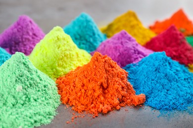 Photo of Colorful powder dyes on grey background, closeup. Holi festival