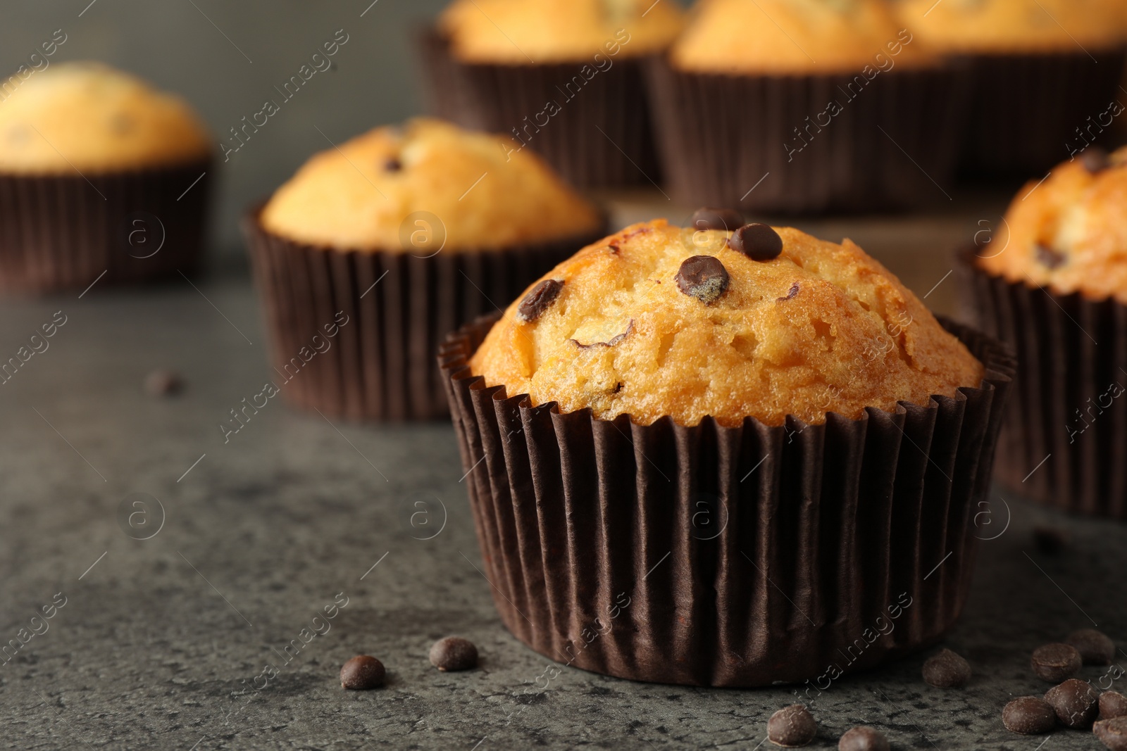 Photo of Delicious freshly baked muffins with chocolate chips on gray table, closeup