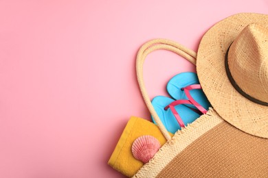 Photo of Bag with beach accessories on pink background, above view. Space for text