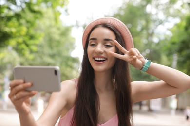 Photo of Beautiful young woman taking selfie outdoors on sunny day