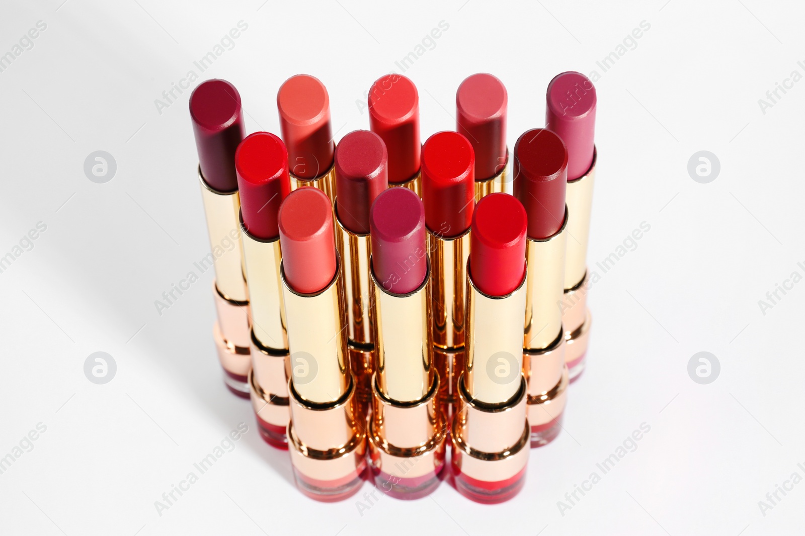 Photo of Set of bright lipsticks in gold tubes on white background