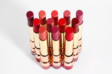 Photo of Set of bright lipsticks in gold tubes on white background