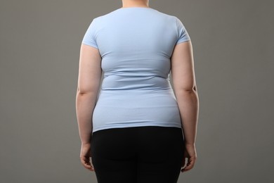 Overweight woman on grey background, back view