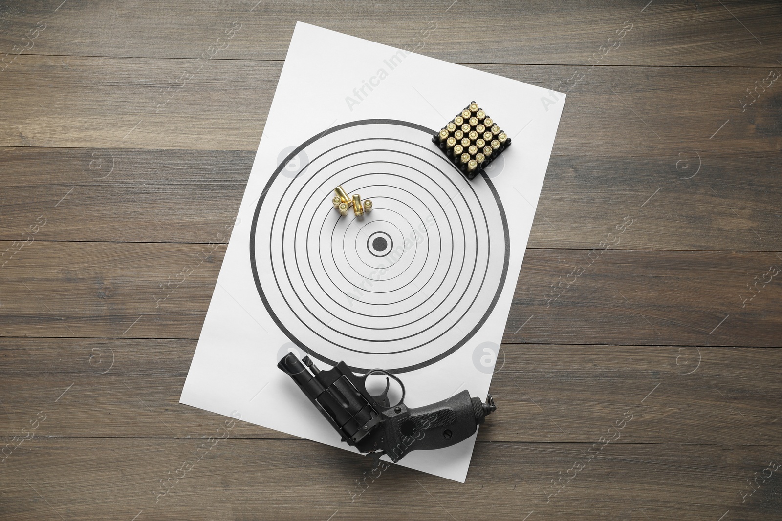 Photo of Shooting target, handgun and bullets on wooden table, top view