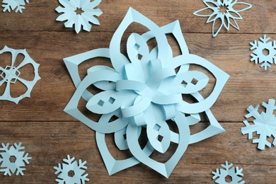 Photo of Many paper snowflakes on wooden background, flat lay