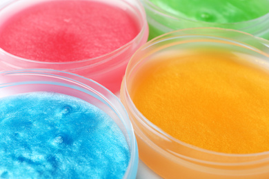 Photo of Colorful slimes in plastic containers, closeup. Antistress toy