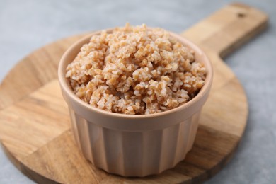 Tasty wheat porridge in bowl on grey table, closeup