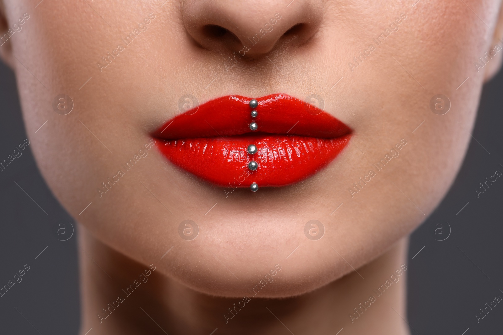 Photo of Young woman with red lips makeup on grey background, closeup