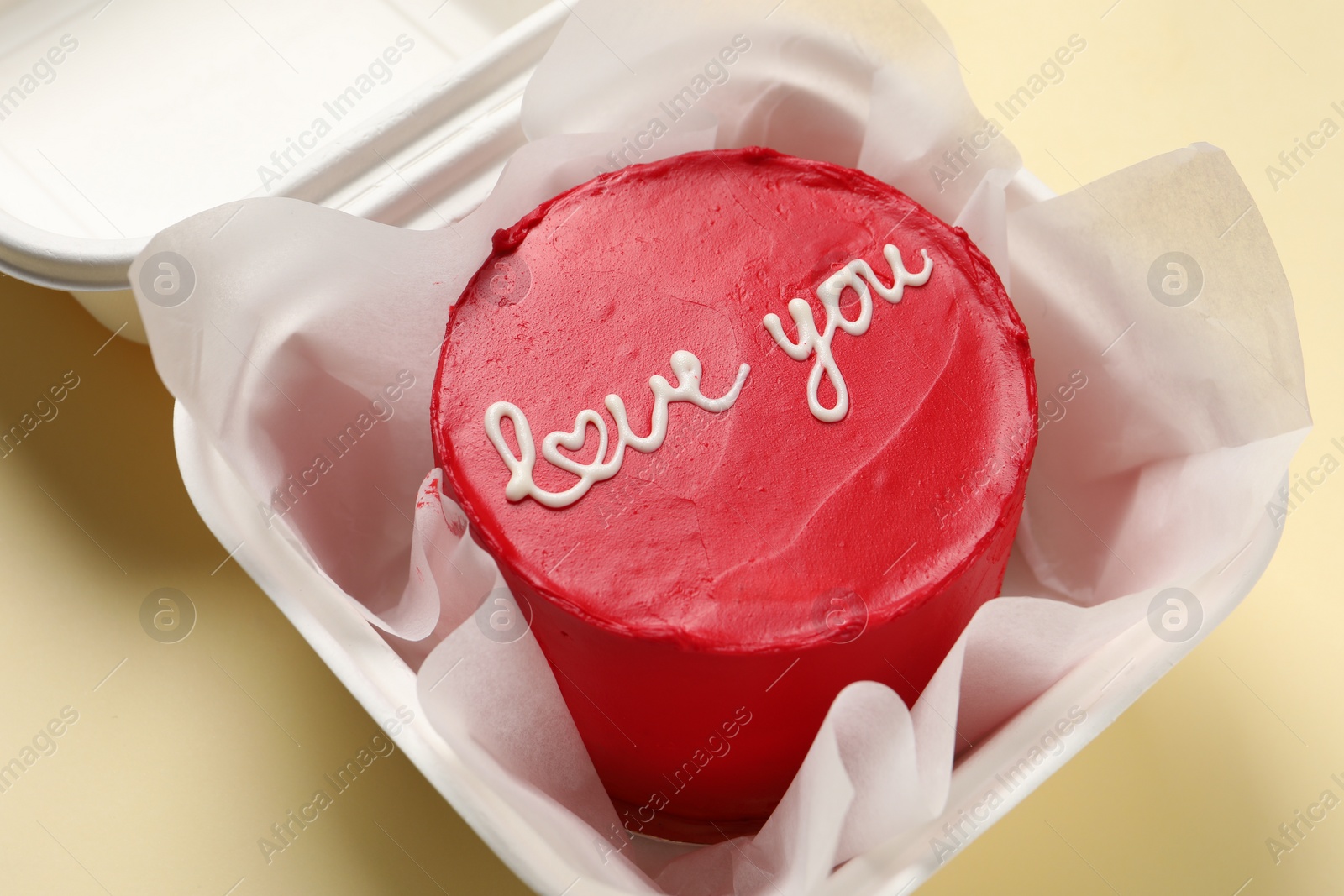 Photo of Bento cake with Love You text in takeaway box on beige table, closeup. St. Valentine's day surprise