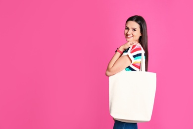 Beautiful young woman with stylish blank eco bag against color background, space for text
