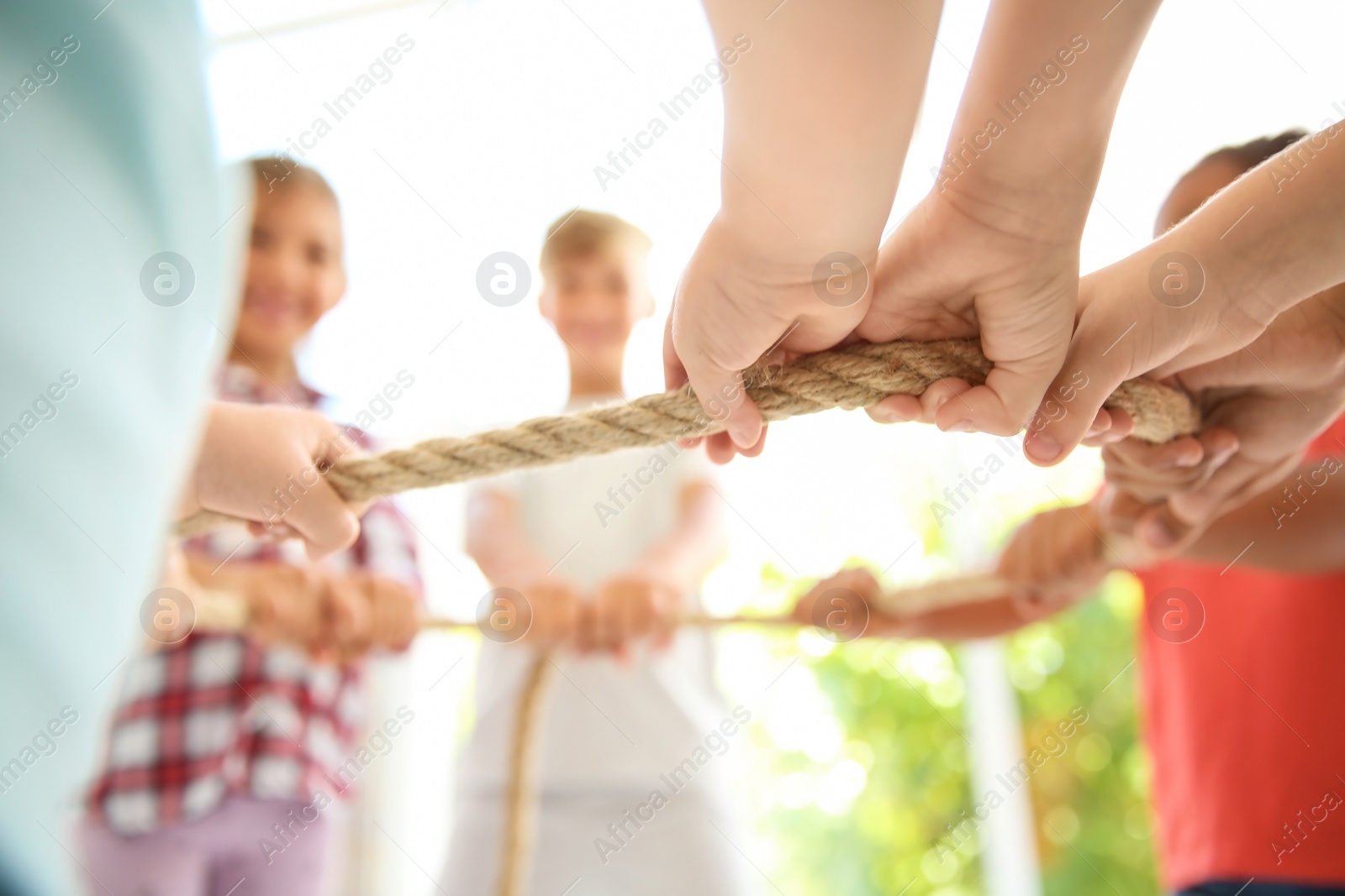 Photo of Little children holding rope on light background, focus on hands. Unity concept