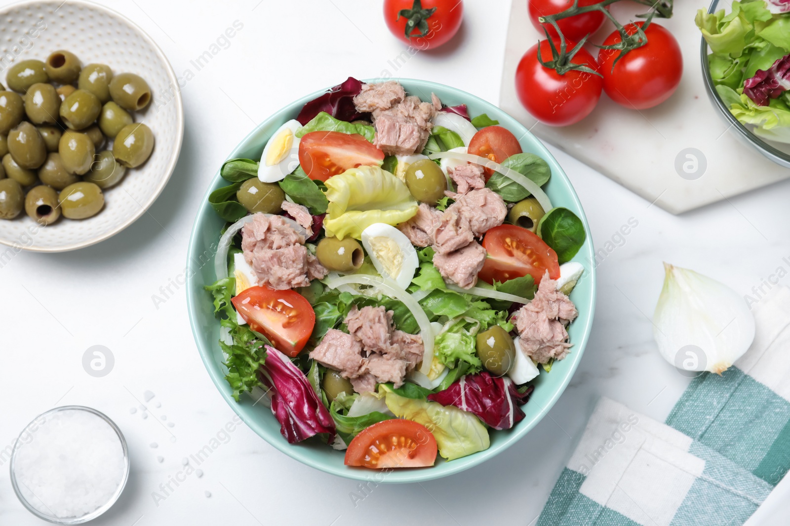 Photo of Bowl of delicious salad with canned tuna and vegetables on white table, flat lay