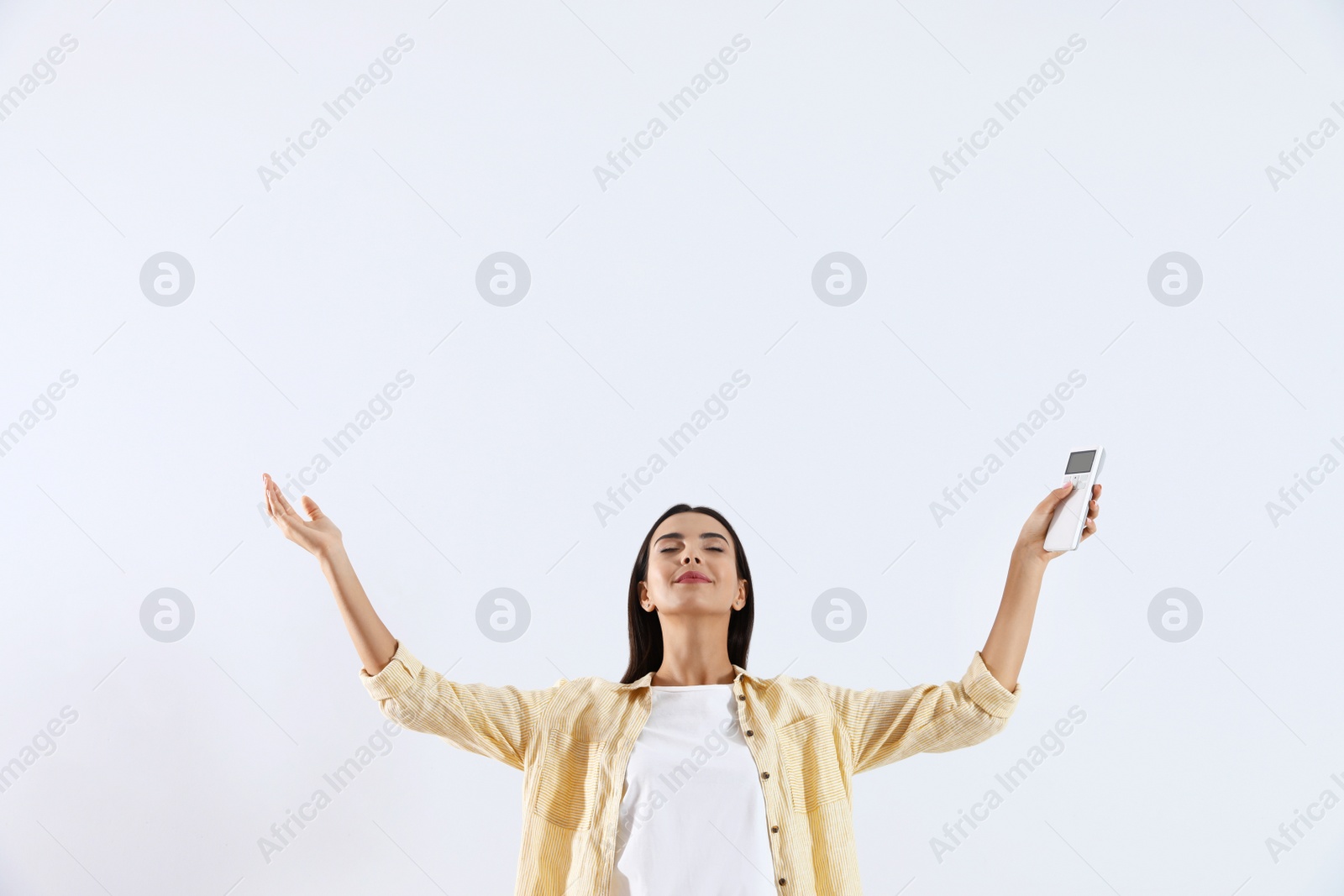 Photo of Young woman with air conditioner remote on white background