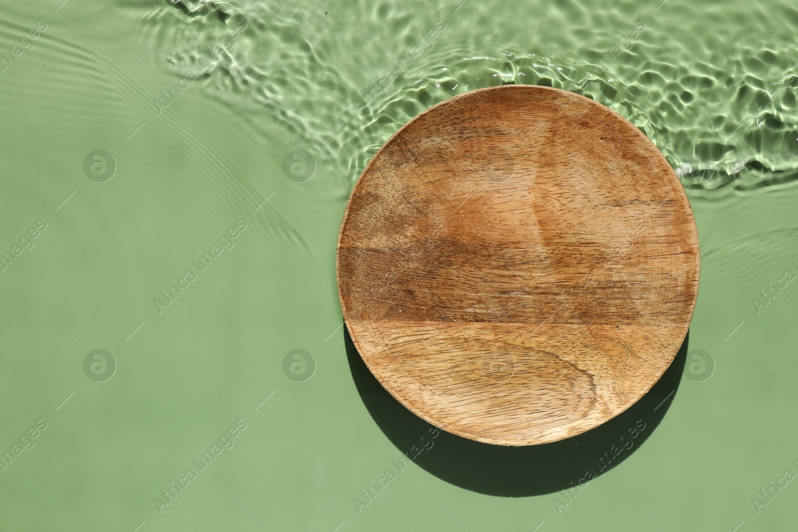 Photo of Presentation of product. Wooden podium in water on green background, top view. Space for text