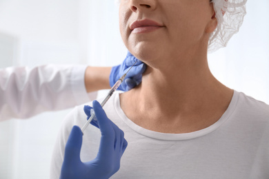 Photo of Mature woman with double chin receiving injection in clinic, closeup