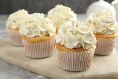 Photo of Tasty cupcakes with vanilla cream on grey table, closeup