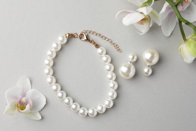 Photo of Elegant pearl earrings, bracelet and orchid flowers on white background, flat lay