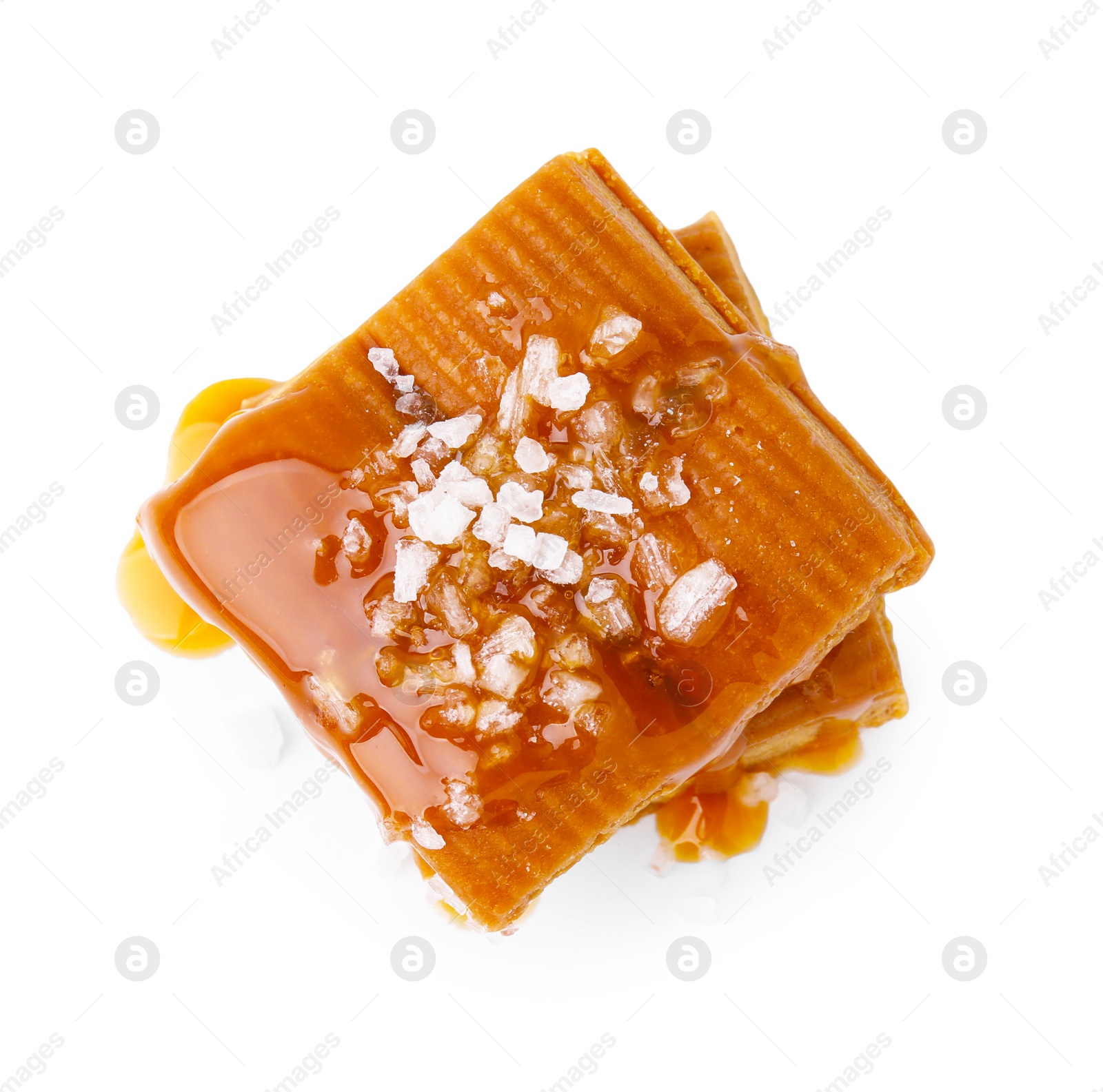 Photo of Yummy caramel candies and sea salt isolated on white, top view