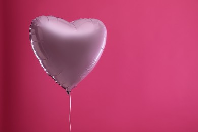 Festive heart shaped balloon on pink background. Space for text