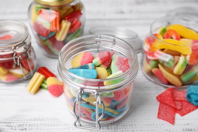 Photo of Tasty jelly candies in different jars on white wooden table