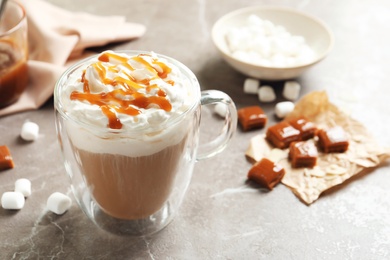 Cup of coffee with caramel topping on grey background