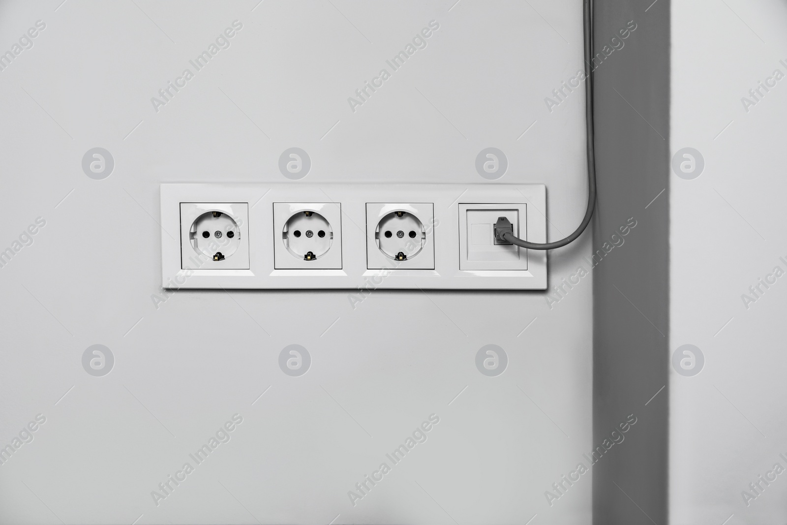 Photo of Power sockets with internet cable on white wall. Electrical supply