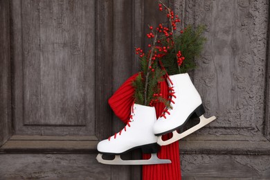 Pair of ice skates with Christmas decor hanging on old wooden door