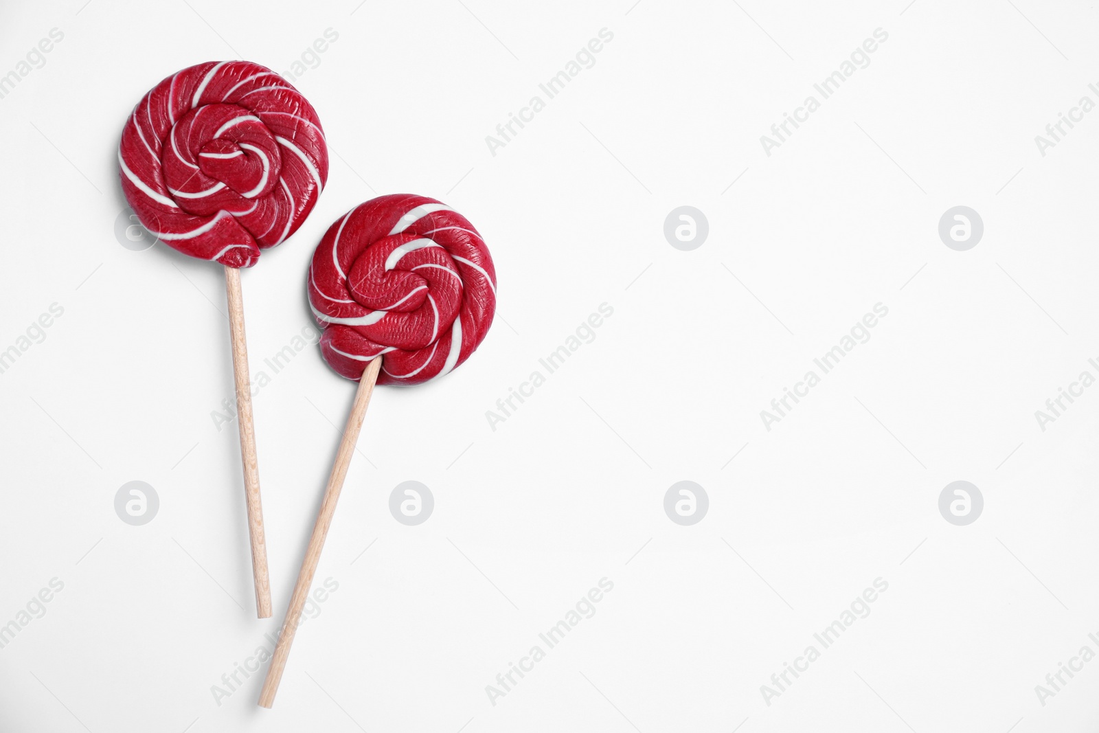 Photo of Sticks with bright lollipops on white background, flat lay. Space for text