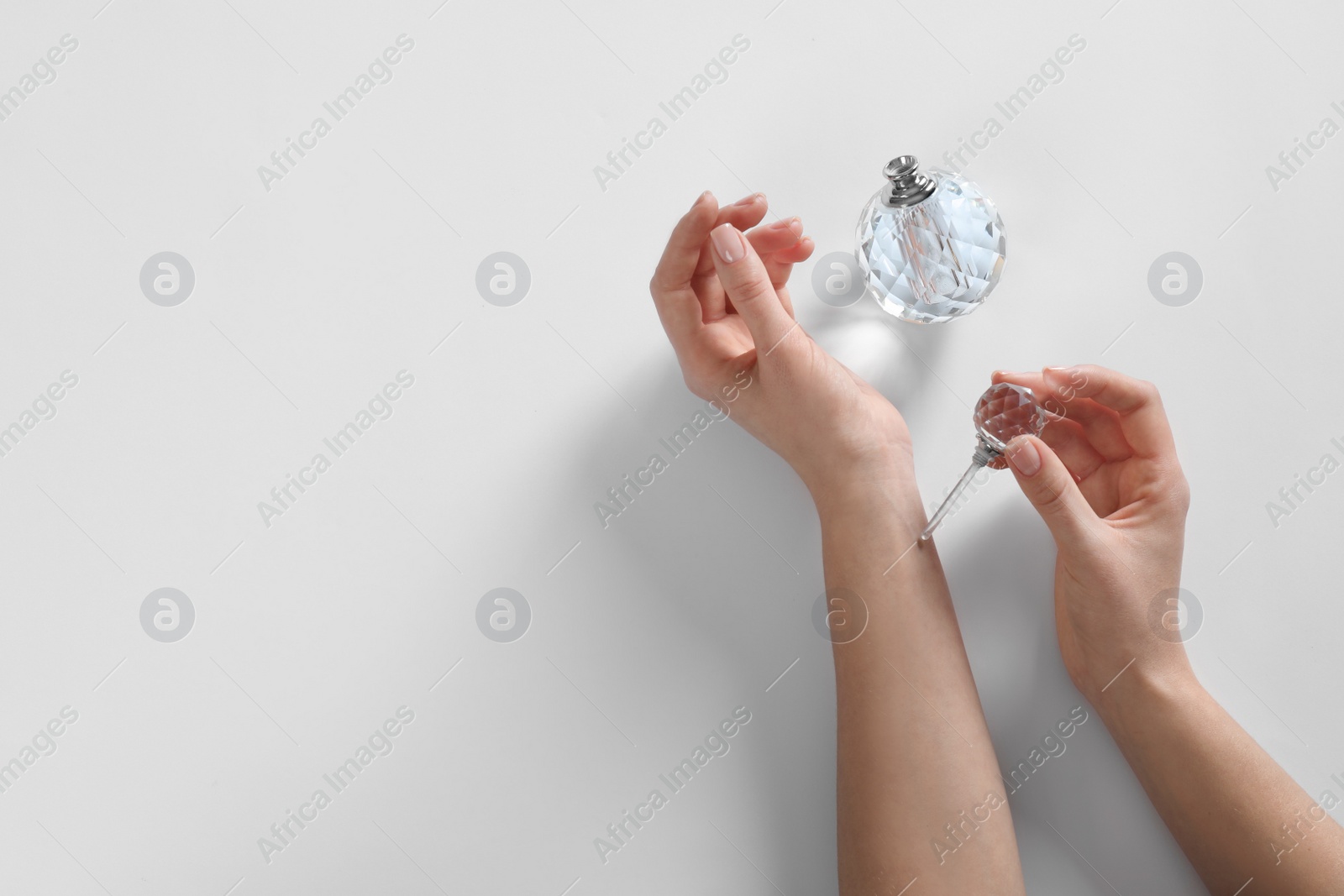 Photo of Woman applying perfume on white background, top view. Space for text