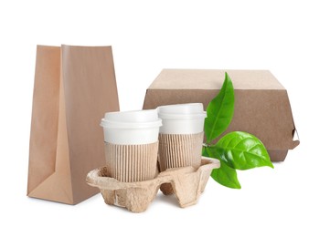 Different containers, coffee cups and green fresh leaves on white background