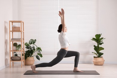 Girl practicing crescent asana on mat in yoga studio. High lunge pose