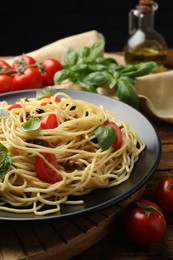 Photo of Delicious pasta with anchovies, tomatoes and basil on wooden table