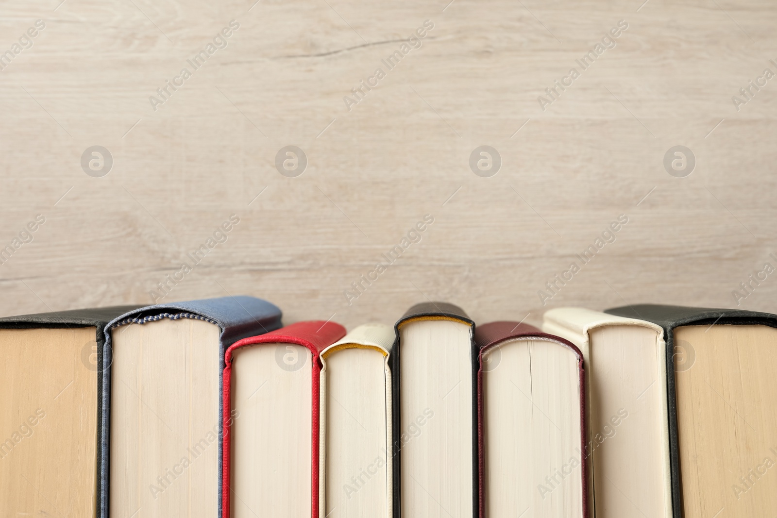 Photo of Many hardcover books on wooden background, space for text