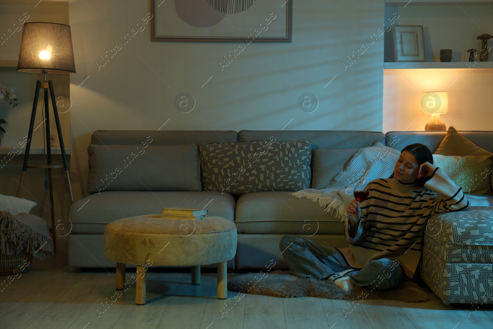 Photo of Woman with glass of wine resting in room at night