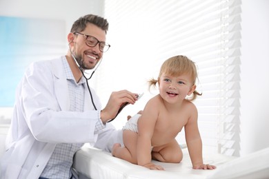 Pediatrician examining baby with stethoscope in clinic