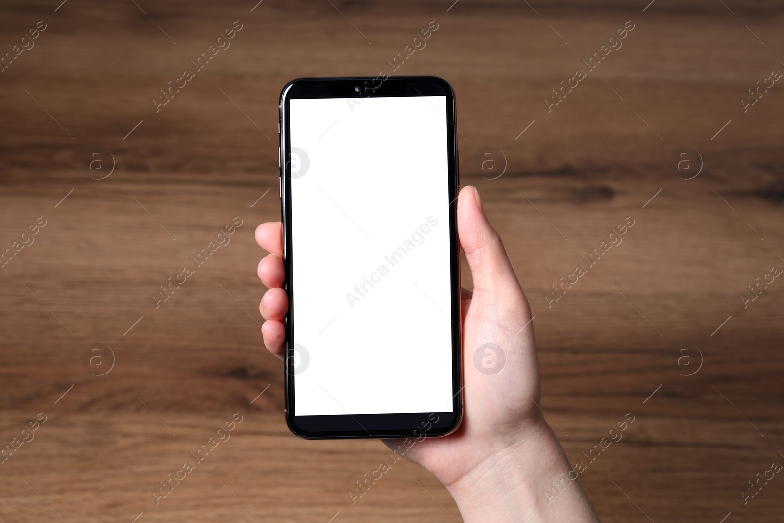 Photo of Woman holding smartphone with blank screen at wooden table, top view. Mockup for design