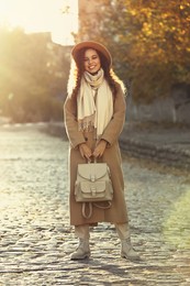 Photo of Full length portrait of beautiful African-American woman with stylish beige backpack on city street