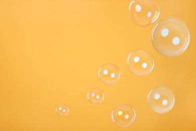 Many beautiful soap bubbles on orange background. Space for text