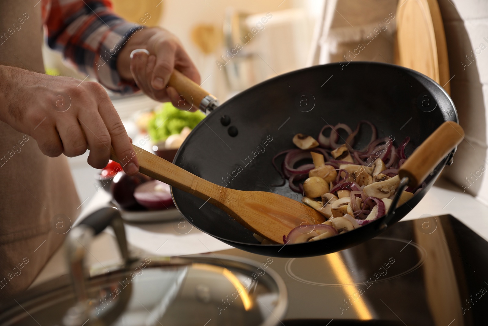 Photo of Man stirring cut vegetables in frying pan, closeup