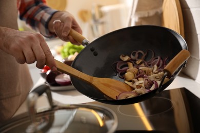 Man stirring cut vegetables in frying pan, closeup