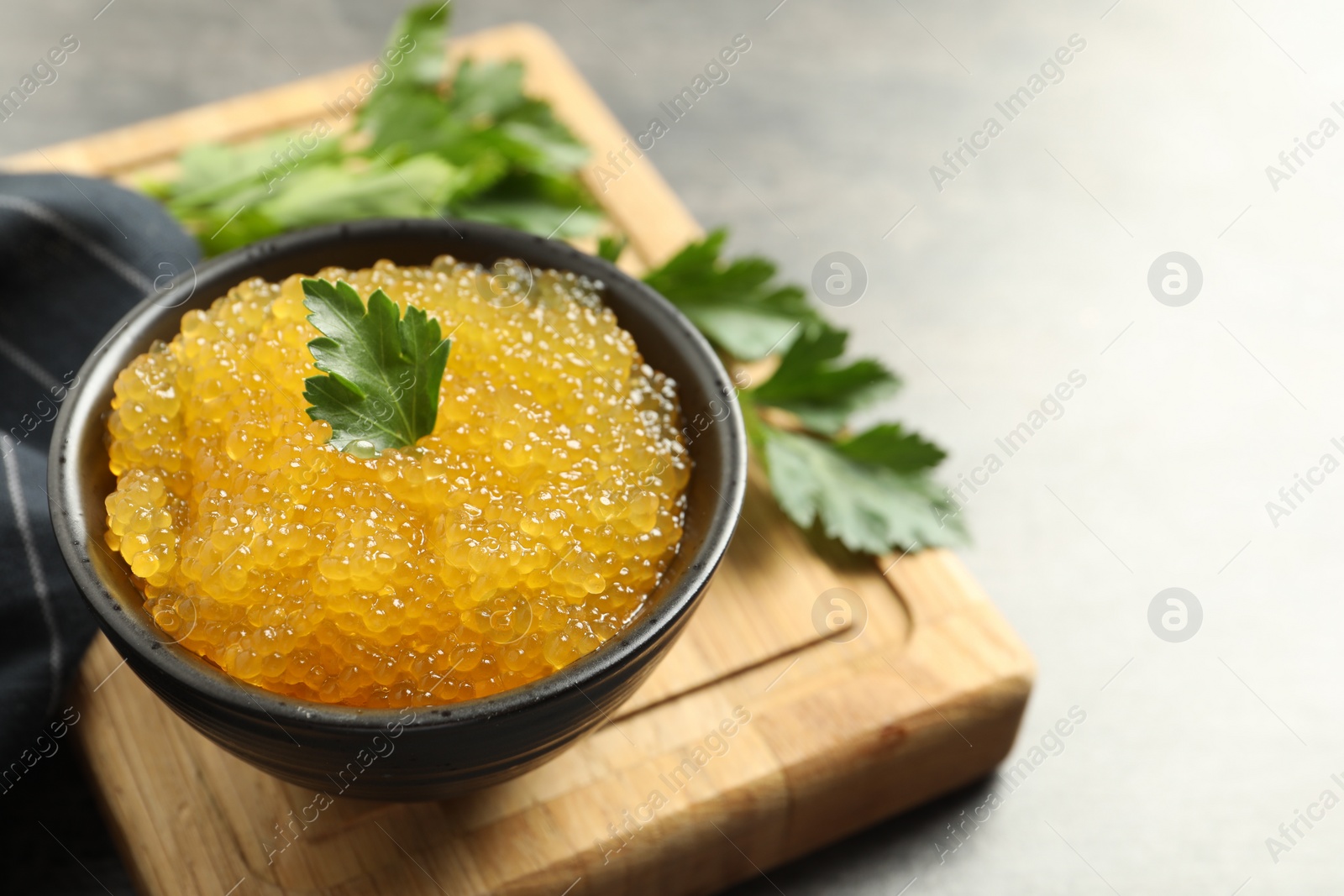 Photo of Fresh pike caviar in bowl and parsley on table, closeup