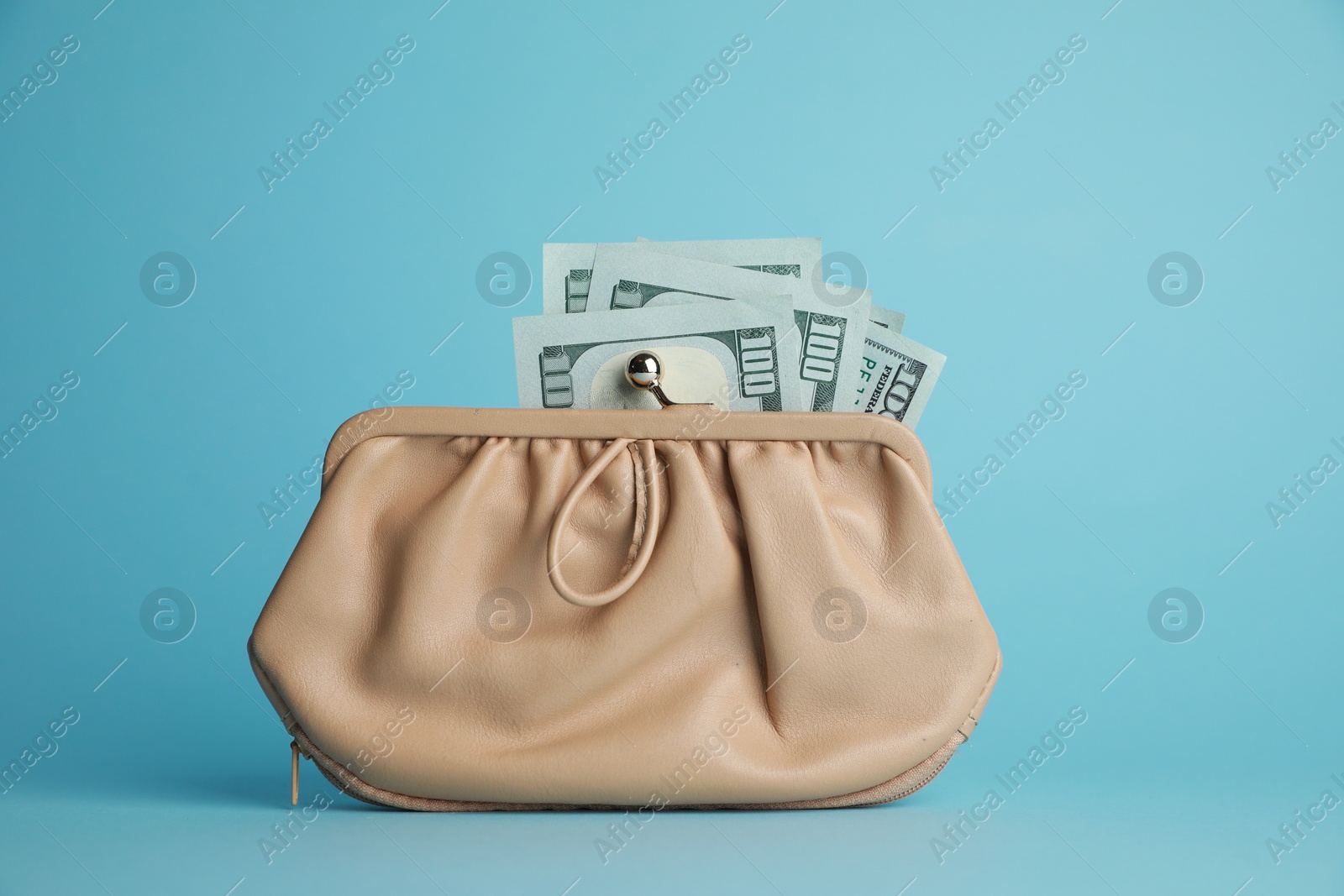 Photo of One stylish leather purse with money on light blue background